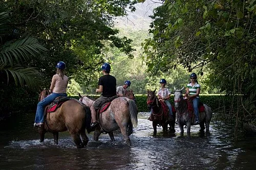 Tourist riding horseback toward La Fortuna Waterfall trail in Costa Rica