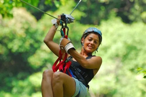Tourist riding a zipline high above the rainforest canopy in La Fortuna