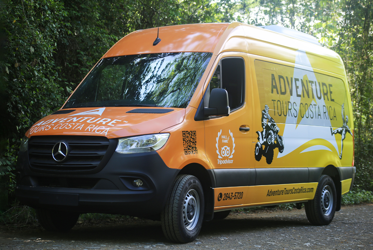 Private shuttle van from San José airport to Jaco parked on a rainforest road.